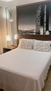 a bedroom with a large white bed with a picture on the wall at Hotel Bonaparte Moderno e versátil in Brasilia +22 photos