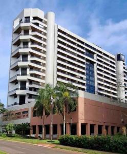 a large building with palm trees in front of it at Hotel Bonaparte Moderno e versátil in Brasilia
