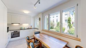 Una cocina con una mesa de madera y algunas ventanas. en Amazing big studio in the city center - Sun 7, en Zúrich