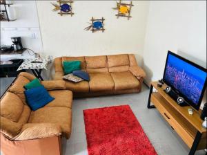 a living room with a couch and a flat screen tv at Sobrado com Piscina Perto Praia in Caraguatatuba