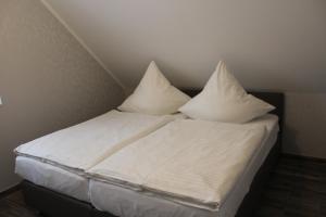 a bed with white sheets and pillows on it at LandBrise in Petersfeld