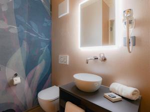 ein Badezimmer mit Toilette, Waschbecken und Spiegel in der Unterkunft Cubilaris Motel in Bad Ragaz