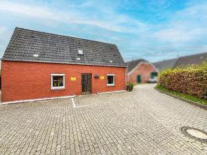 a red brick building on a brick driveway at Ferienhaus am Deich mit Küche, Balkon und Smart-TV in Emden