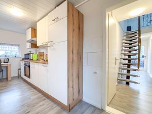 a kitchen with white cabinets and a spiral staircase at Ferienhaus am Deich mit Küche, Balkon und Smart-TV in Emden