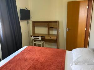 a bedroom with a desk and a bed with a red blanket at Chalé 4 vista para montanha in Penedo