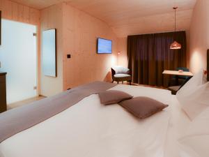 ein Schlafzimmer mit einem weißen Bett und einem Stuhl in der Unterkunft Cubilaris Motel in Bad Ragaz