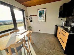 a kitchen with a table and chairs and a window at Fiordland Eco-Retreat -- Panoramic Views -- Hot Tub in Te Anau