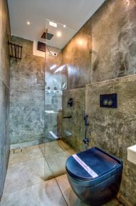 カラングートにあるHotel Pajaros Bluのガラスのシャワーと青いトイレを備えたバスルーム