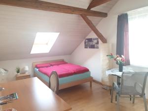 una camera da letto con un letto con lenzuola rosa e un tavolo di Tannenzapfenland, PRIVAT ZIMMER Akasha a Bichelsee