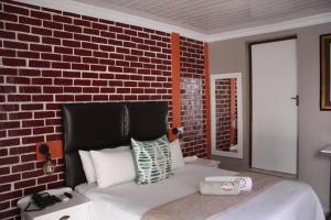 a bedroom with a brick wall and a bed at On Hill Lodge in Bloemfontein