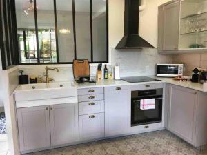 a kitchen with white cabinets and a sink and a stove at Gîte La Maisonnette à Auvers-sur-Oise in Auvers-sur-Oise