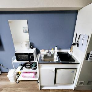 une petite cuisine avec un évier et un micro-ondes dans l'établissement XeroB HOUSE -KOZU sen204, à Osaka