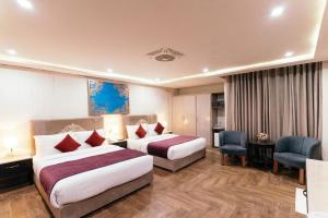 a hotel room with two beds and a desk at Shelton's Ambassador Hotel Blue Area in Islamabad