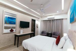 a hotel room with a bed and a desk and a tv at Shelton's Ambassador Hotel Blue Area in Islamabad