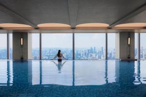 a woman in a swimming pool with a view of a city at Conrad Chongqing - Indulge in the magical 8D city landscape in Chongqing
