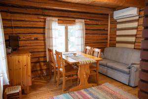 a dining room with a table and a couch at Mäkelän Lomatuvat Cottages in Korkeakoski