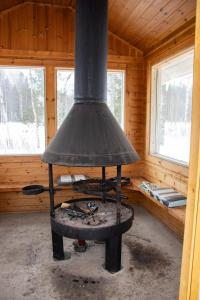 einen Herd in einer Holzhütte mit zwei Fenstern in der Unterkunft Mäkelän Lomatuvat Cottages in Korkeakoski