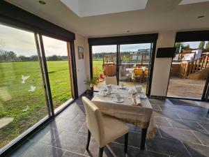 a dining room with a table and chairs and windows at CHAMBRES D'HOTES EpLABONNE in Channay-sur-Lathan