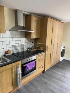 ノッティンガムにあるCity Centre Apartmentの木製のキャビネットとコンロ付きオーブンを備えたキッチン