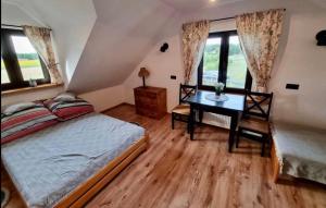 a bedroom with a bed and a desk and windows at Gospodarstwo Agroturystyczne ŻARNOWIEC in Dubicze Cerkiewne