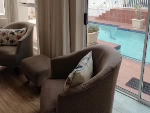 a living room with two chairs and a swimming pool at Villa De Mer in Port Alfred