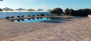 ein Schwimmbad mit Stühlen und Sonnenschirmen an einem Strand in der Unterkunft Borgo Thassos in Astris
