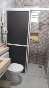 La salle de bains est pourvue de toilettes et d'une porte de douche en verre. dans l'établissement Casa de praia itanhaem, à Itanhaém