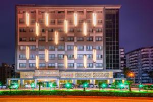 a building with lights on it in a city at Park Dedeman Mersin Marina in Mersin