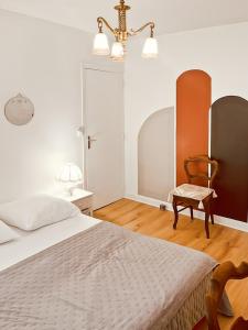 una camera da letto con un letto, una sedia e un lampadario di Maison au coeur de MARCOLES, 2ch, 4pers, jardin a Marcolès
