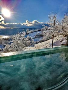 una piscina en la nieve con el sol en el fondo en Moon Lake Bicaz - Casa Oia, en Buhalniţa