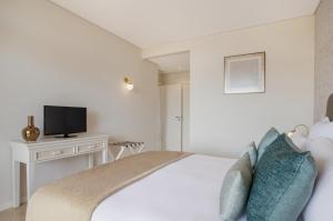 a white bedroom with a bed and a tv at Monte Santo Resort in Carvoeiro