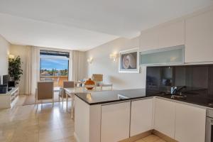 a kitchen with white cabinets and a living room at Monte Santo Resort in Carvoeiro