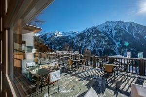 a balcony with tables and chairs and mountains at Farmhotel Moosmair in Campo Tures