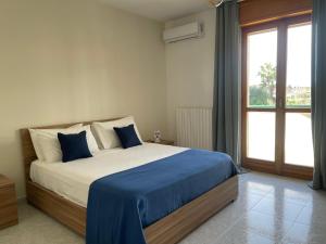 a bedroom with a bed with blue sheets and a window at Gargano Home- Manfredi Homes & Villas in Manfredonia