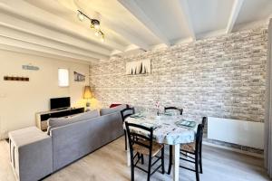 salon ze stołem i ceglaną ścianą w obiekcie Maisonnette refaite à neuf - 300m des plages w mieście Guidel