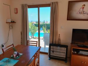 a living room with a dining table and a large window at Kapsalia Holiday Villas in Pissouri