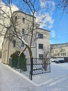 a white building with a tree in the snow at Modern Comfort In The Centre Of Riga! in Rīga