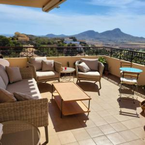 a patio with couches and tables on a balcony at Apartamento duplex en resort de golf y playa in Atamaría