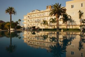 a building with palm trees and a pool of water at Club Hotel Kennedy in Roccella Ionica