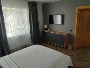 a bedroom with a bed and a flat screen tv at Vinor Cottage in Volosyanka