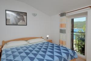 a bedroom with a blue and white bed and a window at Lori Rabac App in Rabac