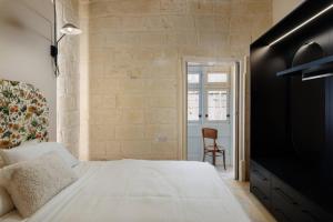 a bedroom with a white bed and a chair at Harbour Heights in Birgu