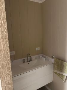 Un baño con un lavabo blanco y un espejo. en Casa barrio Las Lomas 2, en Monte Hermoso 3 fotos más