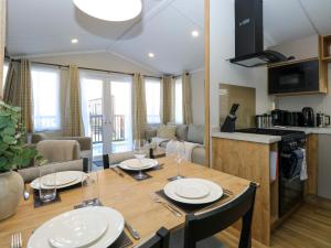 a kitchen and living room with a wooden table with chairs at The Sea Lodge in Norwich