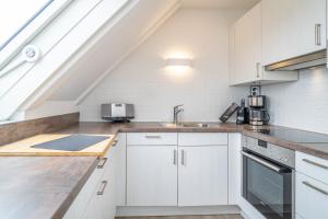a kitchen with white cabinets and a sink at Appartement Haus Wattblick Hus Wattblick in Munkmarsch