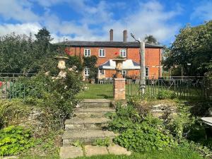 a garden in front of a brick house at Lower Buckton Country Living Big House near Ludlow 6 bedrooms sleep 12 in Leintwardine