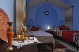 Un dormitorio con dos camas y una mesa con lámpara. en Riad La Famille, en Marrakech
