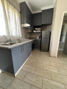a kitchen with gray cabinets and a tile floor at Oewerpark Landgoed Accommodation in Pretoria