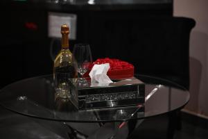 a glass table with a bottle of wine and a box of roses at Love Time in Marseille