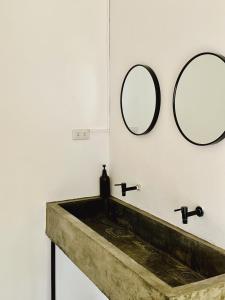 a bathroom with a sink and two mirrors on the wall at Pig Dive Hostel Moalboal in Moalboal